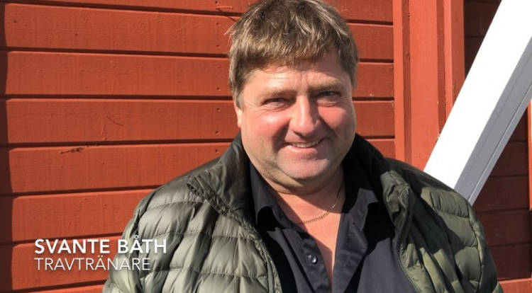 Svante Båth ler in i kameran. Bakom en röd stallvägg på Wången