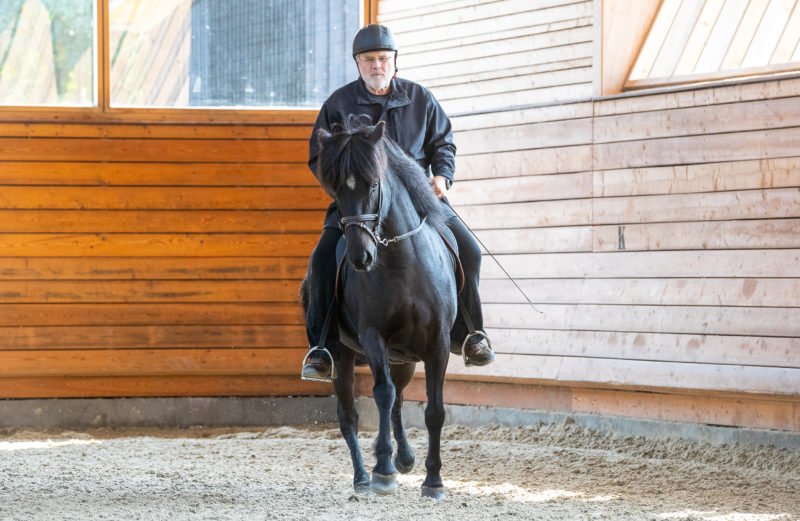 Eyjolfur Isolfsson rider en svart islandshäst i ett ridhus