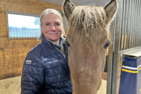 Christine Wadefjord står i en box tillsammans med en islandshäst.